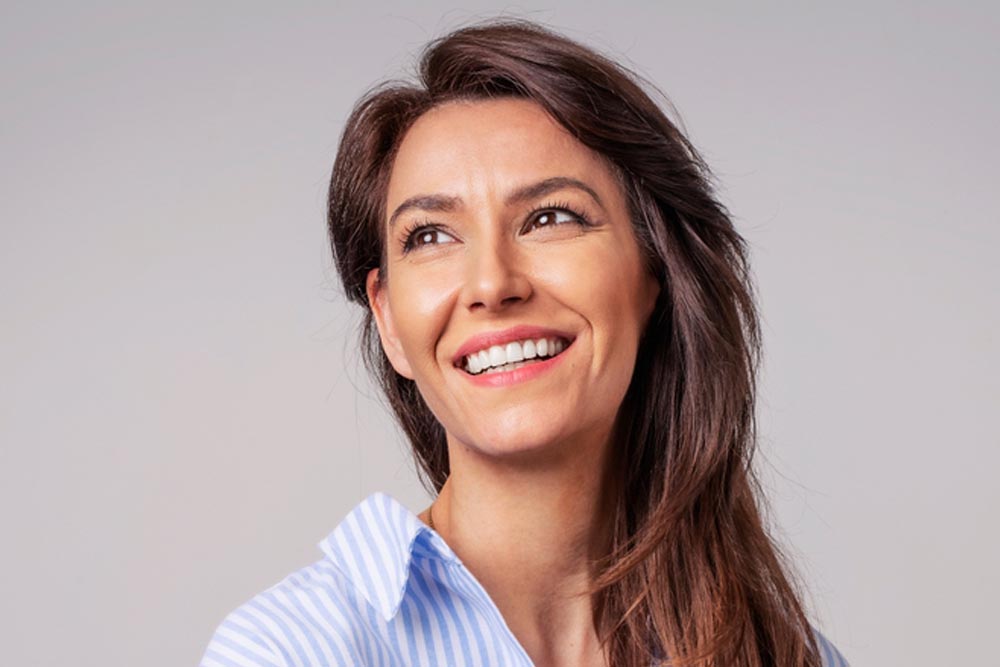 Smiling,Brunette,Businesswoman,Sitting,Against,Gray,Background.,Confident,Female,Professional