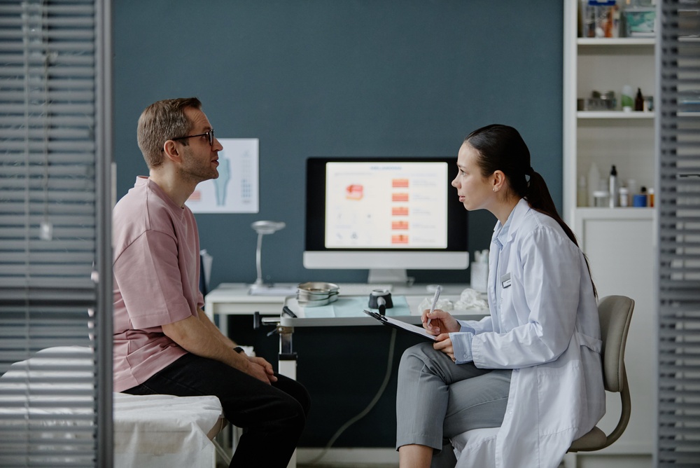 Caucasian,Middle,Aged,Man,Sitting,On,Examination,Table,Consulting,With