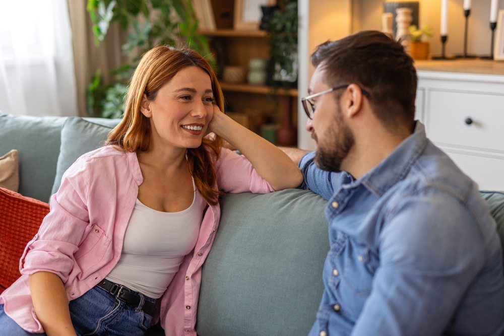 Couple,Is,Sitting,On,A,Sofa,,Engaged,In,Conversation.,Moment