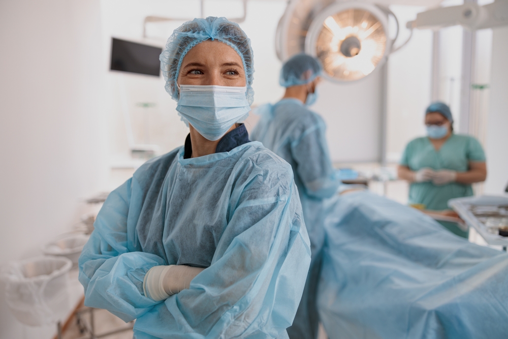 Female,Surgeon,In,Mask,Standing,In,Operating,Room,With,Crossing